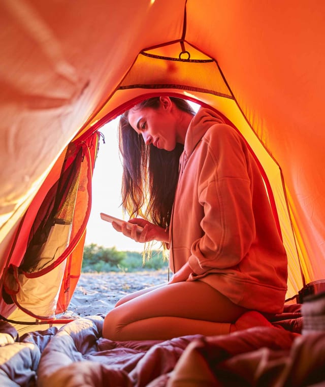 beautiful-young-woman-using-cellphone-in-camp-tent-SGXMCUZ.jpg